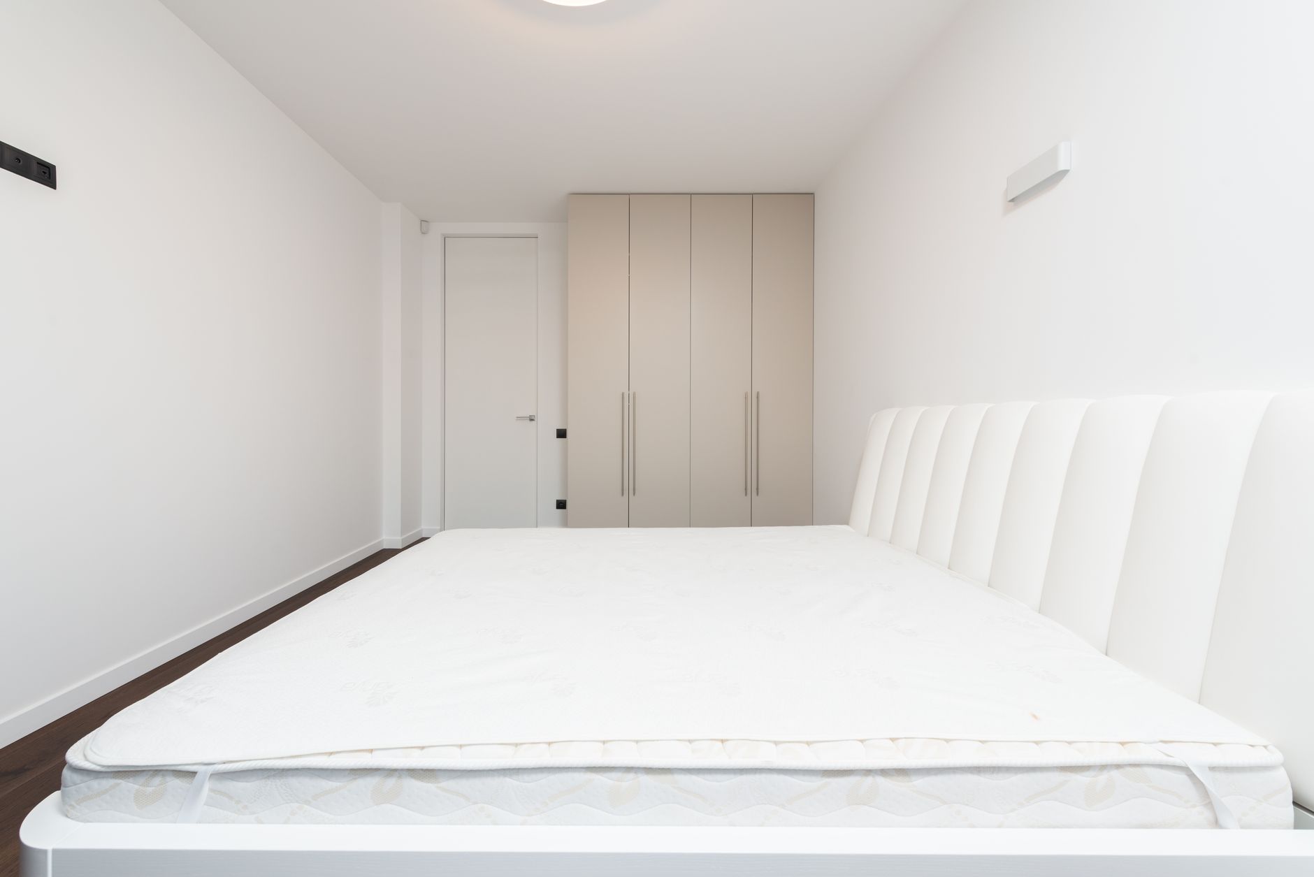 Xử lý nệm bị mốc, hôi, xẹp lún. - Contemporary minimalist bedroom featuring a white mattress and sleek wardrobe under soft lighting.
