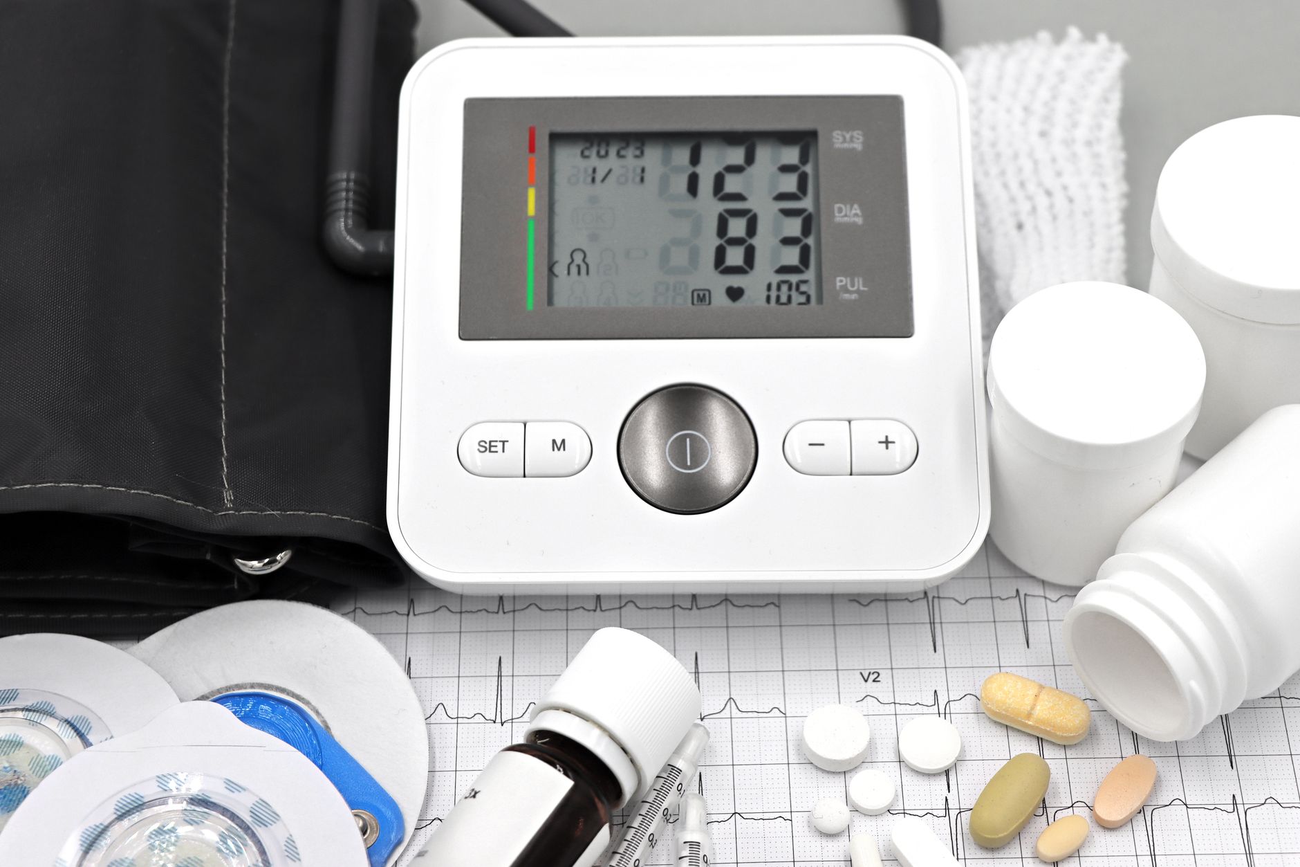 Nệm tốt cho người cao huyết áp - Close-up of medical equipment including blood pressure monitor, pills, and ECG printout.