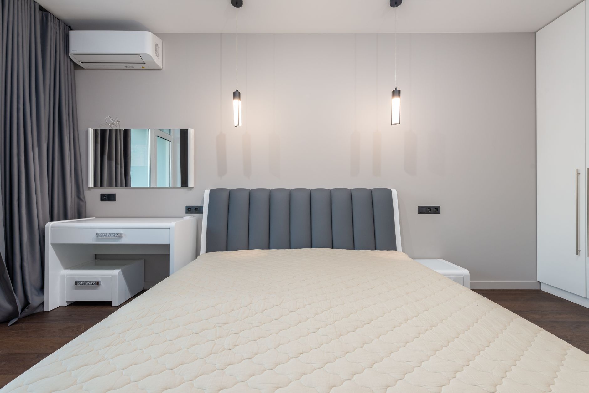 Nằm nệm cao su có bị nóng lưng không - Sleek minimalist bedroom design featuring a plush bed, pendant lighting, and modern furnishings.