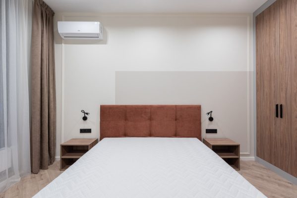 Cách chọn nệm cho phòng ngủ máy lạnh - Modern bedroom interior with big comfortable bed and small bedside tables with large wardrobe in apartment