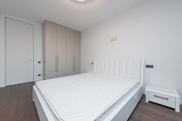 Cách khử mùi hôi trên nệm hiệu quả - Bright minimalist bedroom featuring a white bed and contemporary design.