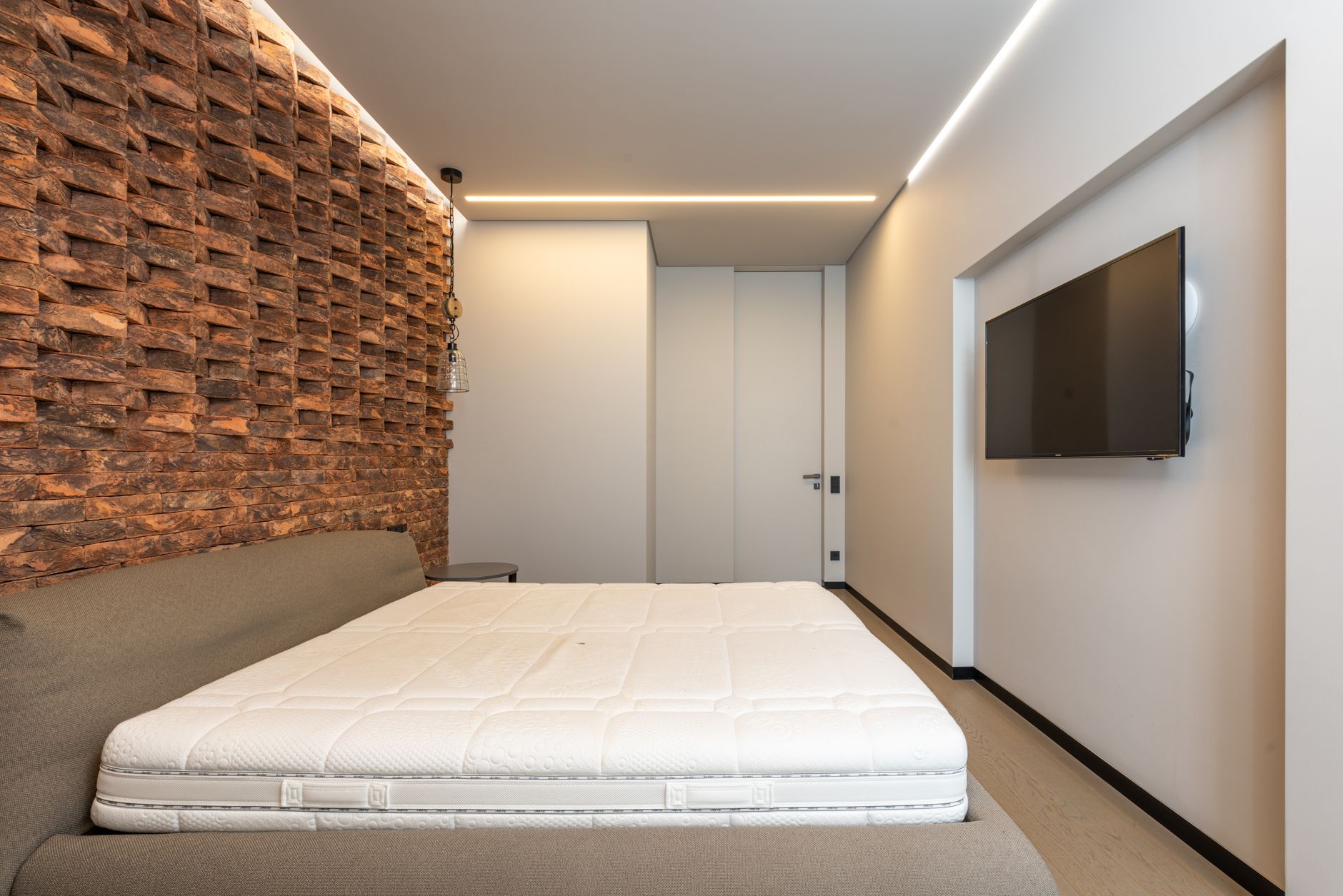 Nệm bị mốc nguyên nhân và cách xử lý - Comfortable be with soft mattress in stylish minimalist bedroom with modern TV and creative brick wall