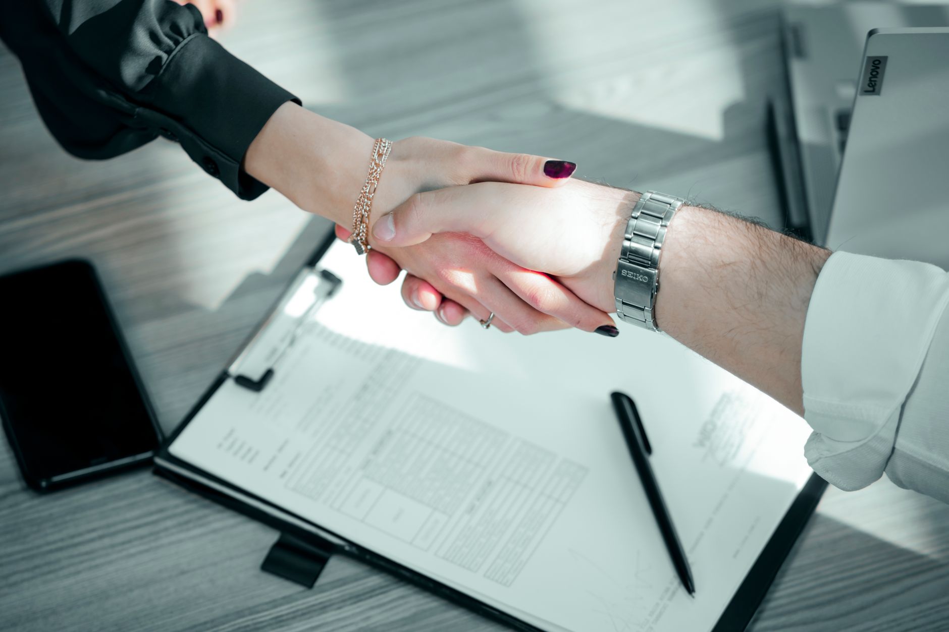 Mua nệm vào tháng nào rẻ nhất - Close-up of a professional handshake over a contract, symbolizing a successful business deal.