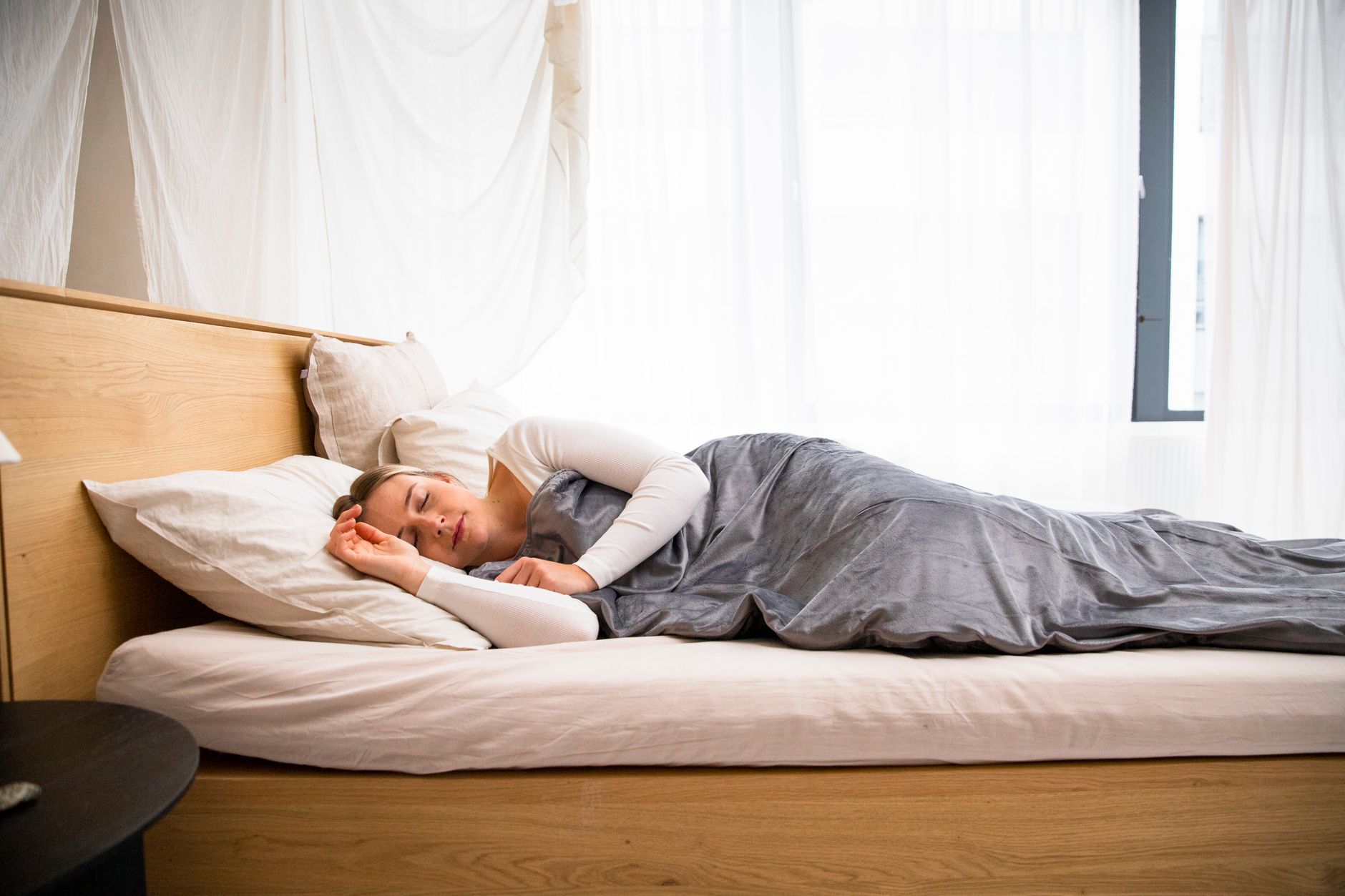 Nệm tốt cho người cao huyết áp - A woman peacefully sleeping in a well-lit modern bedroom with minimal decor.
