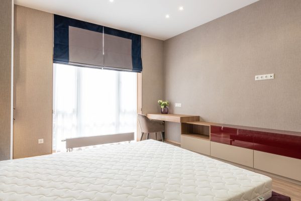 Nệm cho người béo phì trên 100kg - Interior of modern bedroom with mattress on bed placed against wooden cupboard and table with green plant near big window