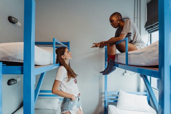 Nệm tốt cho học sinh sinh viên - Two women engaging in conversation on bunk beds in a modern dormitory room.