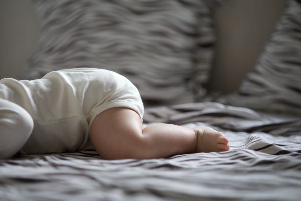 Nên chọn nệm gì cho trẻ sơ sinh - Sweet image of a baby resting peacefully on a cozy bed in soft lighting.
