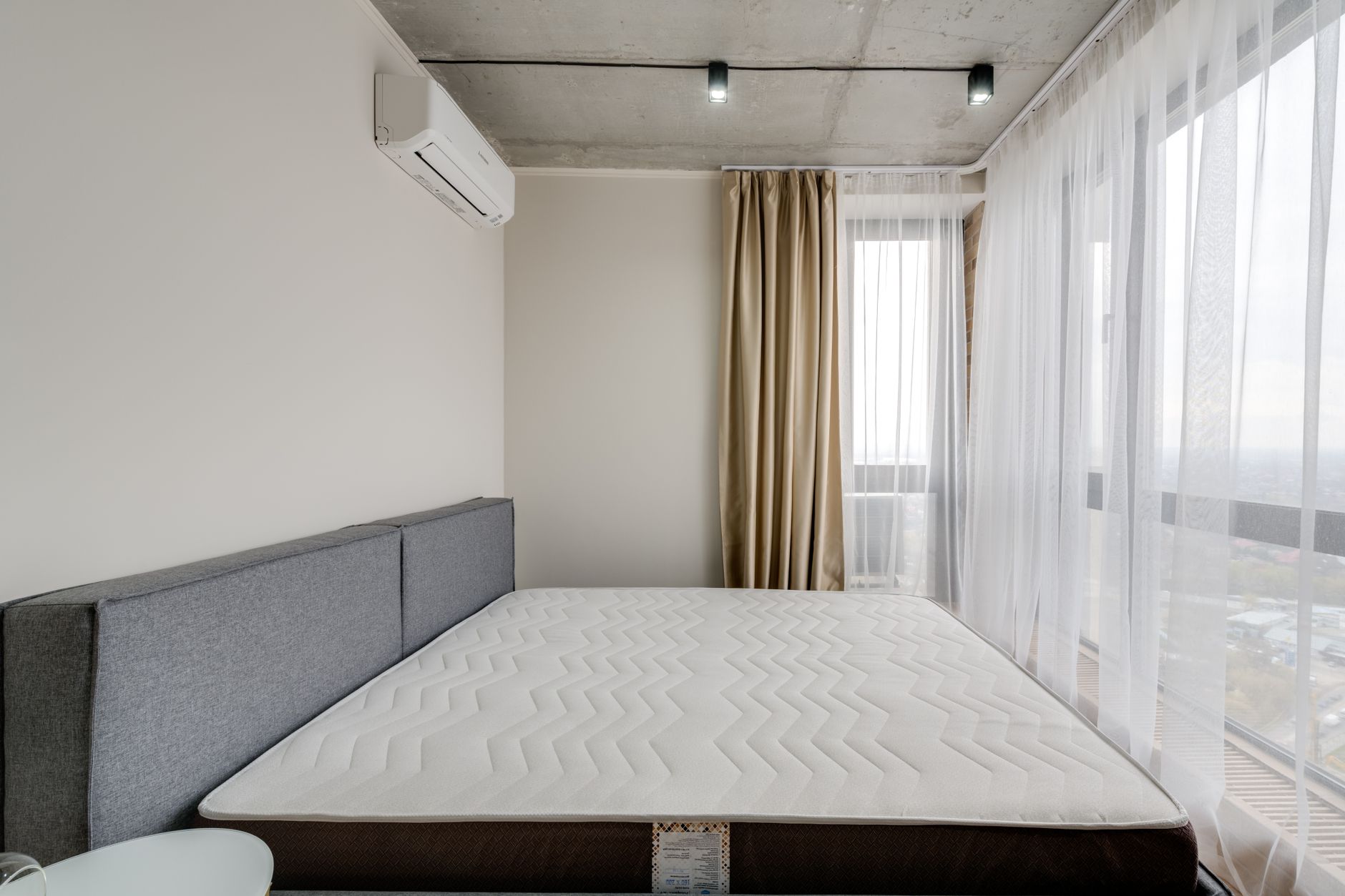Nệm bị xẹp lún phải làm sao - Spacious modern bedroom with a clean mattress and large windows for natural light.