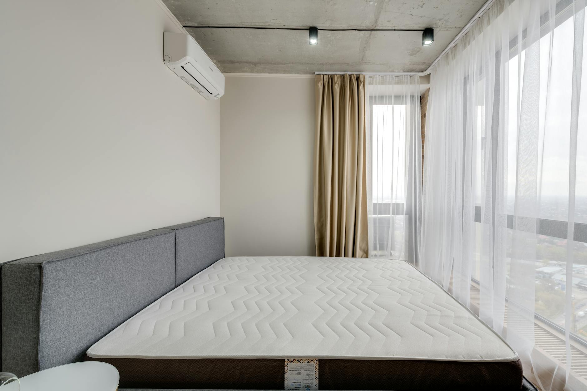 Xử lý nệm bị mốc, hôi, xẹp lún. - Spacious modern bedroom with a clean mattress and large windows for natural light.
