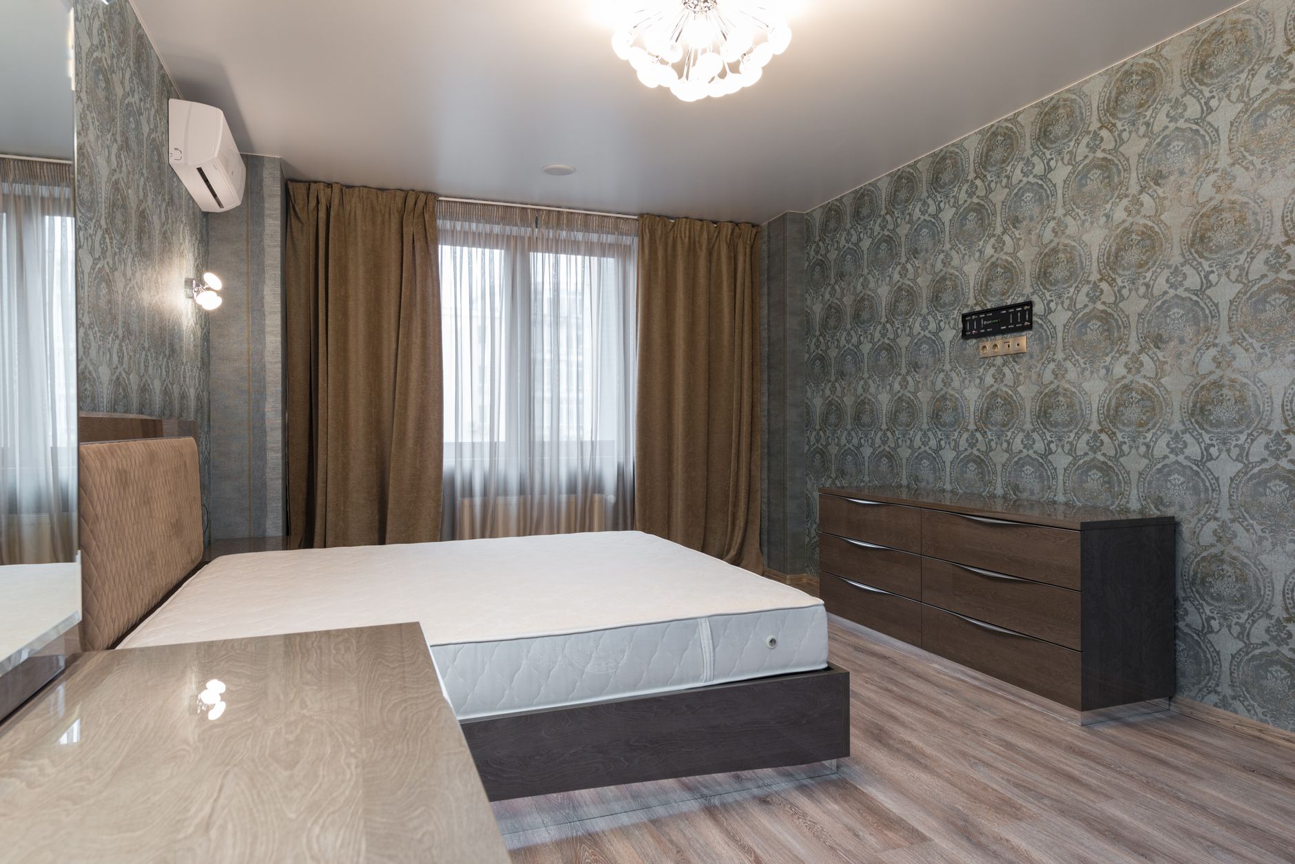 Nệm hơi, nệm nước, nệm thông minh – các dòng nệm đặc biệt. - Interior of bedroom with air conditioning above bed placed near window with curtains and dresser