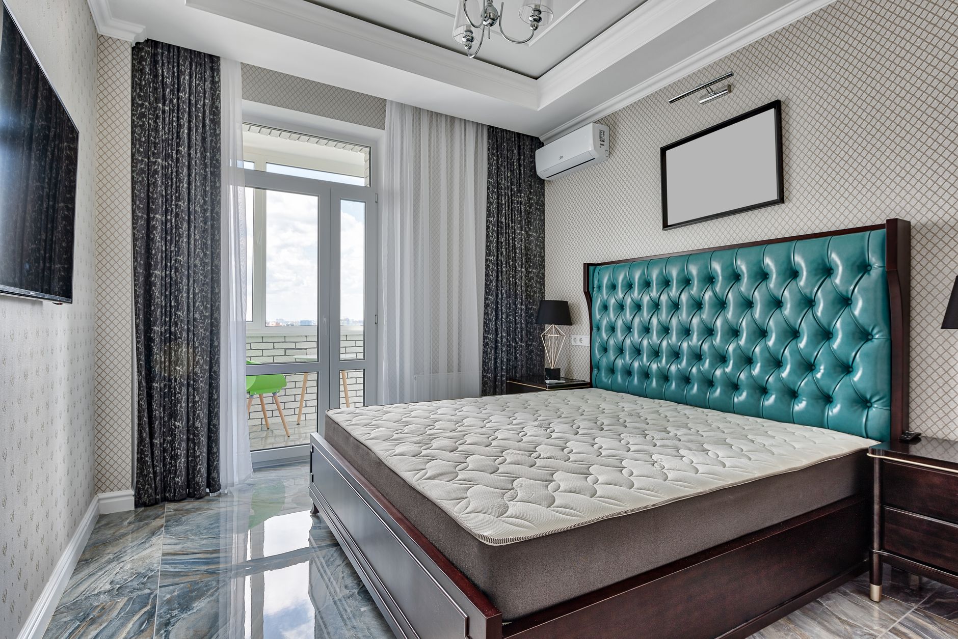 Cách chọn nệm cho phòng ngủ máy lạnh - Bed with mattress between bedside tables on tiled floor in apartment with television on ornamental wall