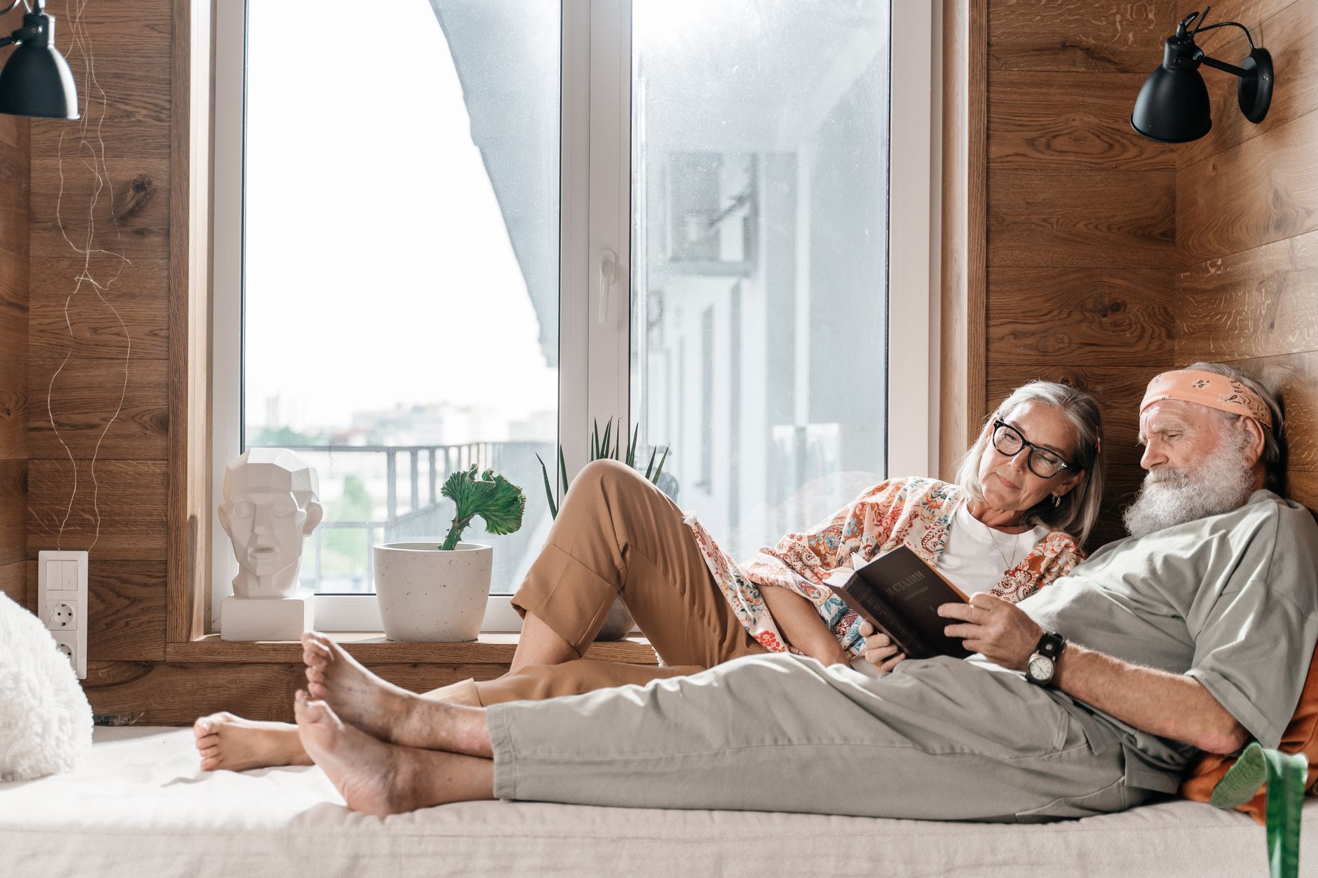 Nệm tốt nhất cho người già trên 60 tuổi - A senior couple enjoying a peaceful moment reading together indoors, exemplifying love and relaxation.