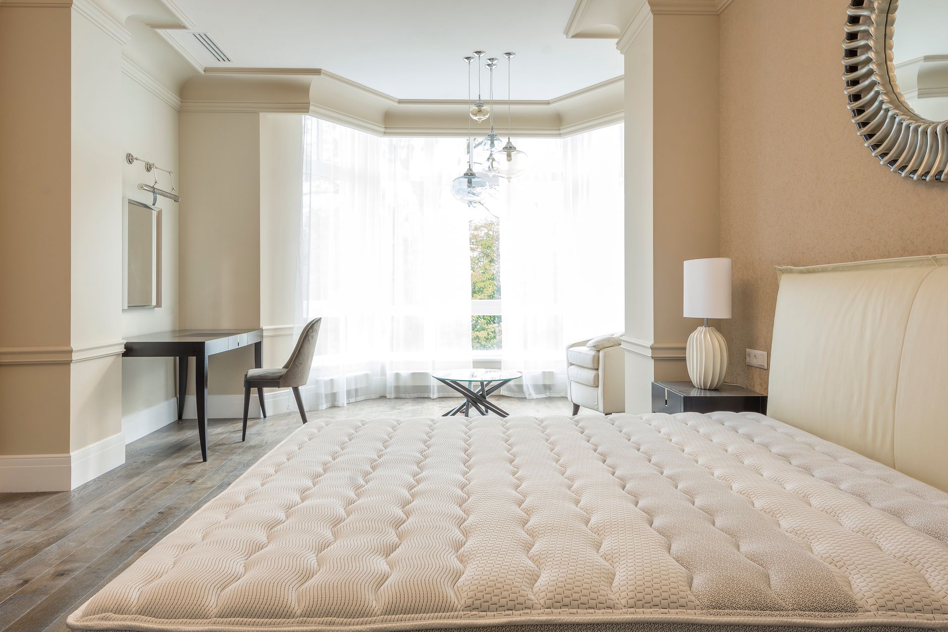 Nệm chống đau lưng cho người ngủ nghiêng - Elegant spacious bedroom with modern furniture, featuring large windows and abundant natural light.
